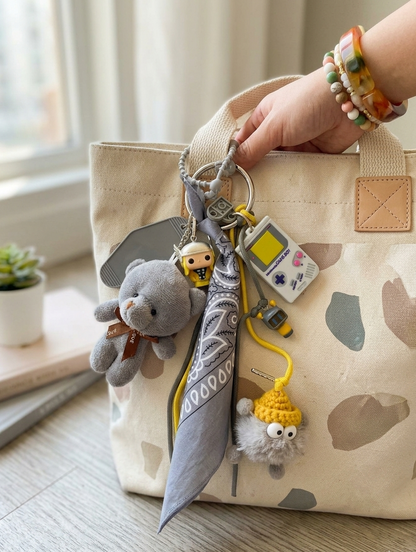 Accessoire de sac Pop et coloré avec pompon gris et jaune et pendentifs ludiques, issu de la Tribu gribouilles